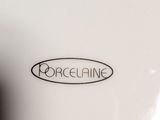 the lid of a white porcelain bowl with a black and white logo on it