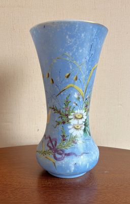un vase bleu avec des fleurs posé sur une table