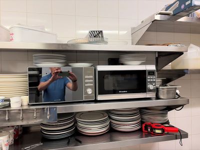 a man taking a picture of a microwave in a kitchen
