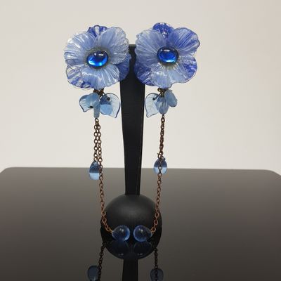 a black vase with blue flowers on it on a table