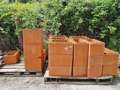 un tas de briques posé sur une palette à côté de quelques buissons