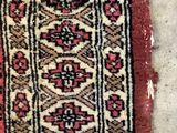 an old rug with a red border on a white floor