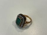 a close up of a gold ring with a green stone on it
