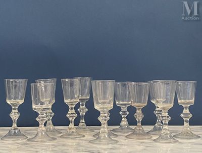 plusieurs verres à vin vides alignés sur une table, avec un mur bleu en arrière-plan