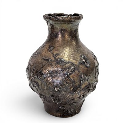 a silver vase that is sitting on a white surface