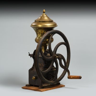 un moulin à café à l'ancienne, avec un socle en bois et un couvercle en laiton