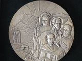 a silver medal with a picture of a group of people on it