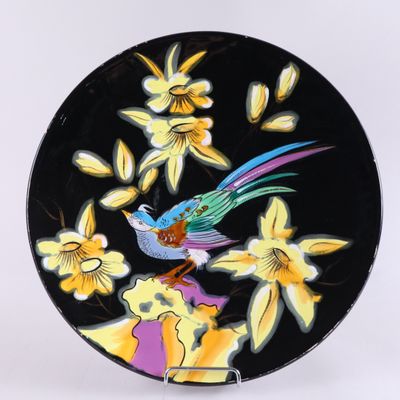 une assiette noire décorée d'un oiseau et de fleurs colorés