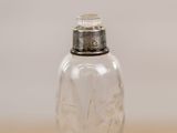 a glass bottle with a silver lid sitting on a table