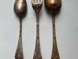 three spoons, a fork and a spoon on a white surface
