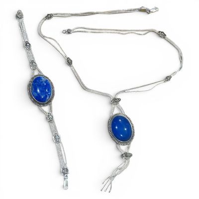silver necklace with blue stone and tassel on white background