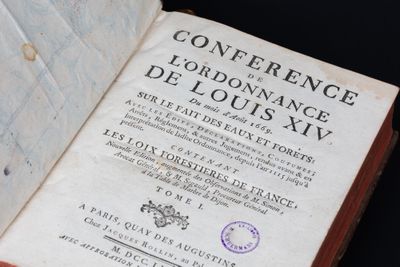 un livre ouvert, sur lequel est apposé un tampon, posé sur une table