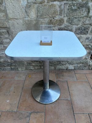 une petite table sur laquelle est posé un panneau, posée sur un sol en briques