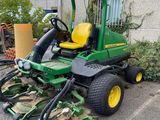 a picture of a green lawn mower parked in front of a building