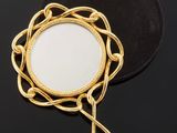 a close up of a mirror on a black surface with a chain around it