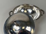 a silver plate with a lid on a white table