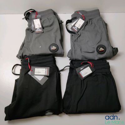 trois paires de pantalons pour homme, noirs et gris, avec leurs étiquettes encore attachées