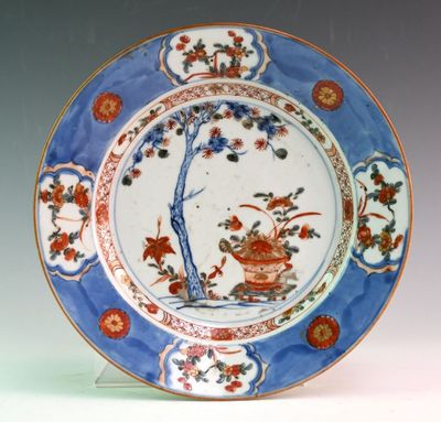 a blue and white plate with a tree and flowers on it
