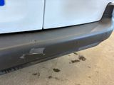 the front bumper of a white van with a hole in it