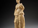 a statue of a woman standing on a block with her hands in her pockets