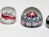 four glass eggs with different designs are lined up on a white surface