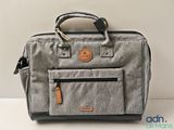 an image of a grey bag with a leather handle on a white surface