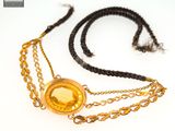collier avec un pendentif doré et une chaîne ornée d'une pièce d'or sur fond blanc