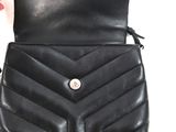 someone is holding a black purse with a button on it
