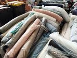 a large pile of mattresses and blankets in a warehouse