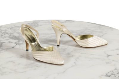 des chaussures blanches à talons hauts posées sur une table en marbre, sur fond blanc