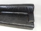 black leather sofa with gold piping on the armrests