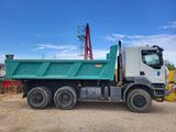 a green dump truck that is parked in the dirt