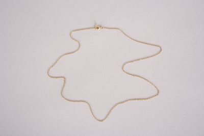 the gold necklace is on a white surface with a gold chain around it