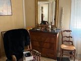 a room with a dresser, chair, mirror, and other items in it