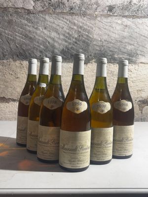 six bottles of wine are lined up on a counter in front of a stone wall