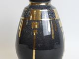 a black and gold vase sitting on a white surface