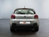 the rear of a silver car in a room with a white wall