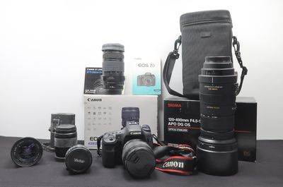 a lot of cameras and lenses on the table