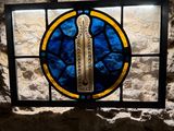 a stained glass window in the corner of a stone wall
