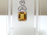 pendentif en saphir jaune et diamants exposé dans un coffret en acrylique transparent