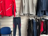 des vêtements suspendus à un mur dans un magasin de vêtements, à côté d'une chaise bleue
