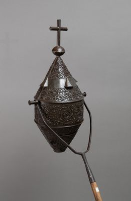 an old metal bell with a wooden handle and a cross on top