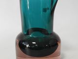 a blue glass vase with a brown base on a white surface