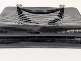 a black crocodile skin purse with gold hardware on top of it