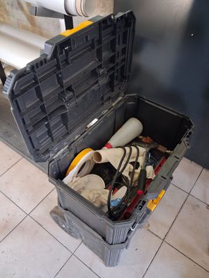 une boîte à outils contenant des outils, posée sur un sol carrelé