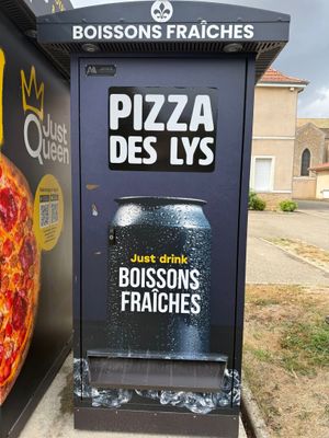a large pizza sitting next to a trash can on the side of the road