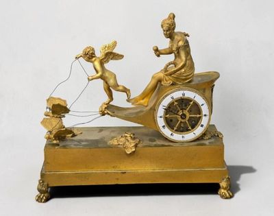 une horloge en or ornée d'anges et représentant un homme dans une calèche