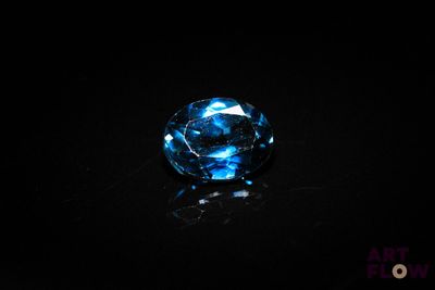 a close up of a blue diamond on a black surface