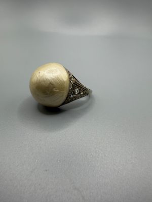 un gros plan d'une bague ornée d'une perle posée sur une table