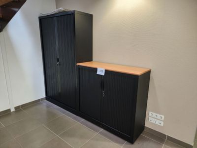 une armoire noire sur laquelle est accrochée une pancarte, dans un coin de la pièce